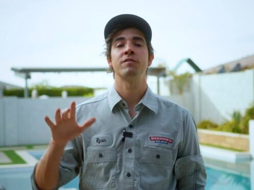 A man stands in front of a backyard pool